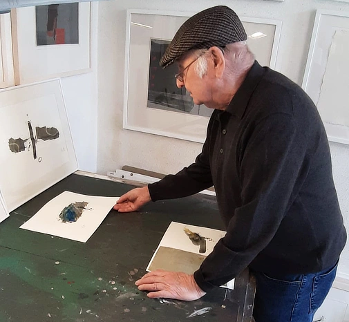Josef Müller examines his ink works on paper.